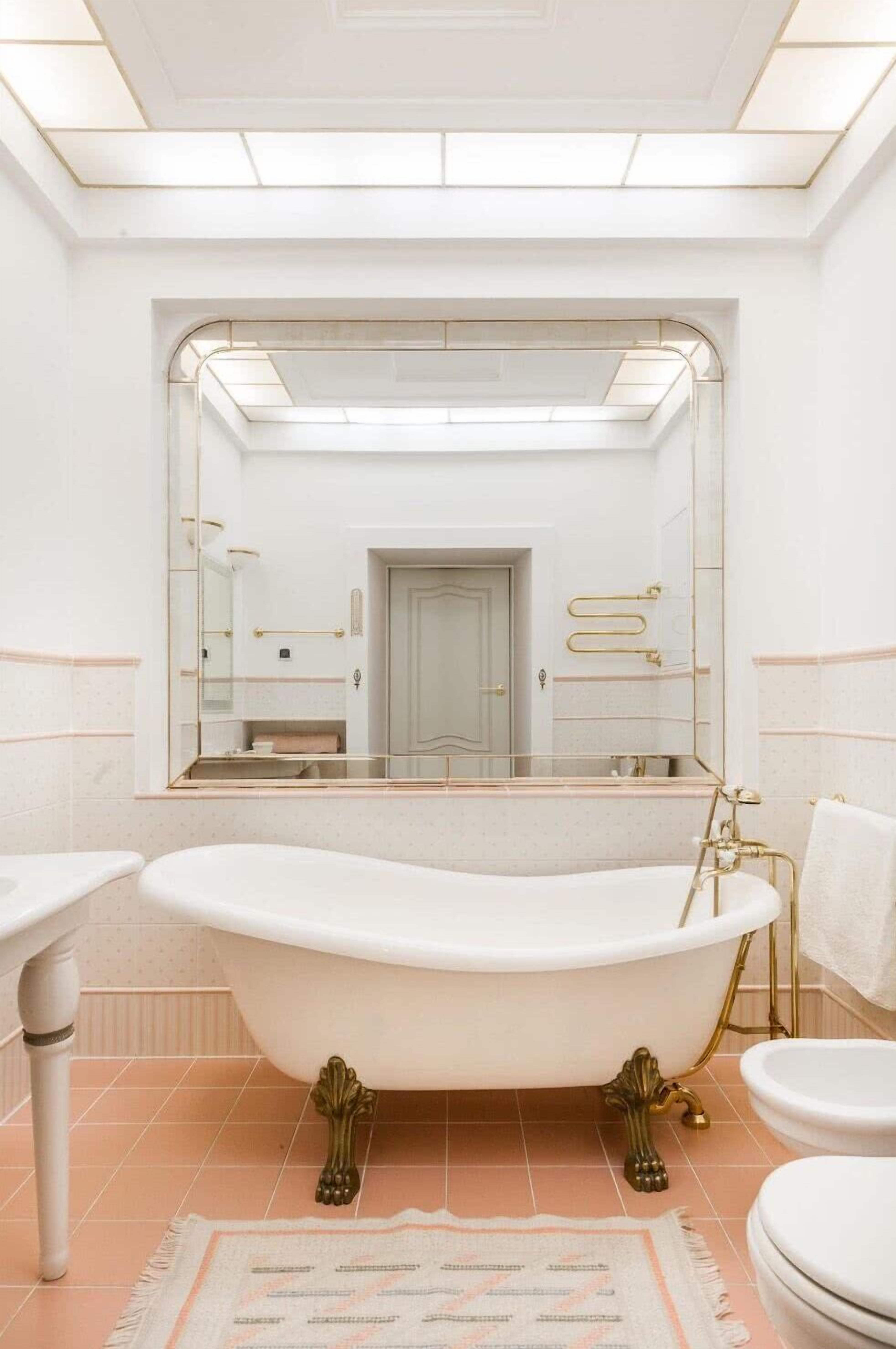 Un baño con una bañera independiente, un espejo grande y un inodoro.