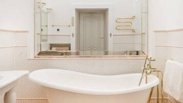 A bathroom with a freestanding bathtub, a large mirror, and a toilet.