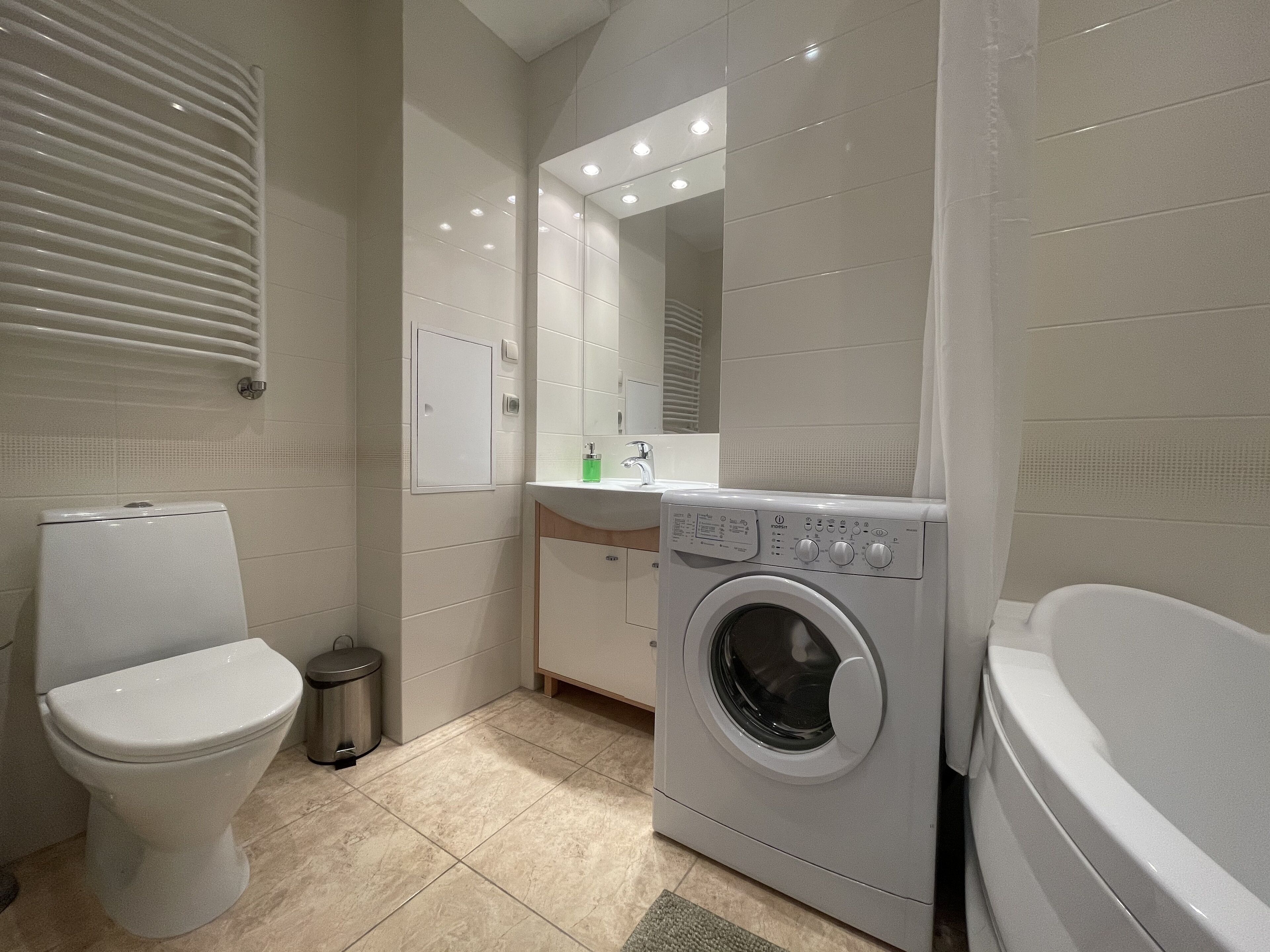 A modern bathroom with a toilet, washing machine, and sink.