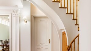 Un interior espacioso con una escalera de madera y una puerta blanca.