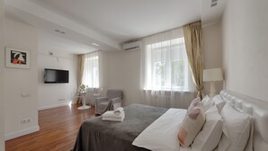 Una habitación de hotel moderna con una cama grande, un televisor de pantalla plana, una silla y un escritorio.