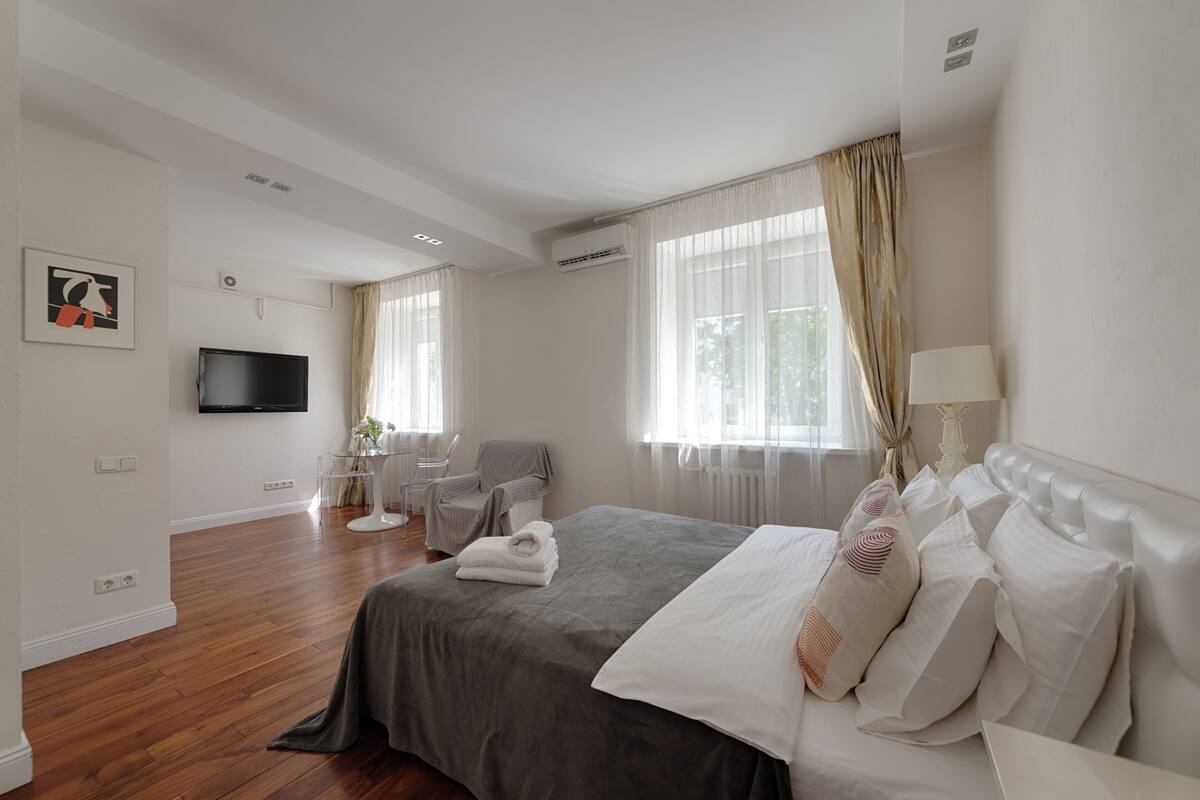 A modern hotel room with a large bed, a flat-screen TV, a chair, and a desk.