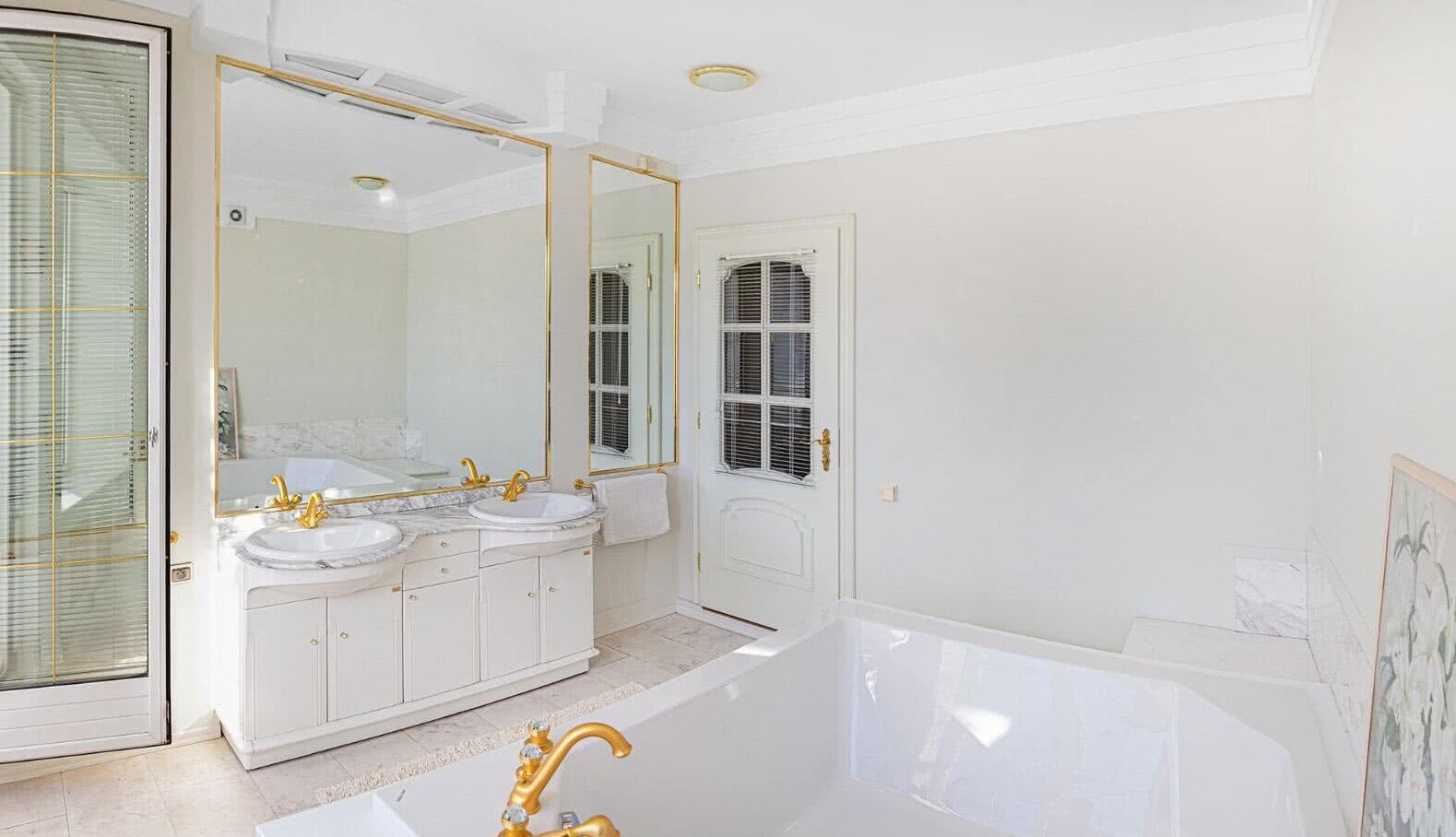 Une salle de bain spacieuse avec une grande baignoire, deux lavabos et un grand miroir.