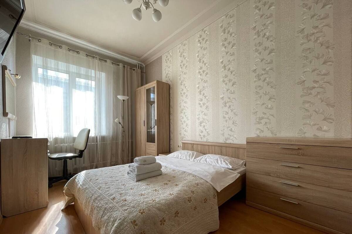 A bedroom with a bed, a wooden dresser, a desk, and a chair.