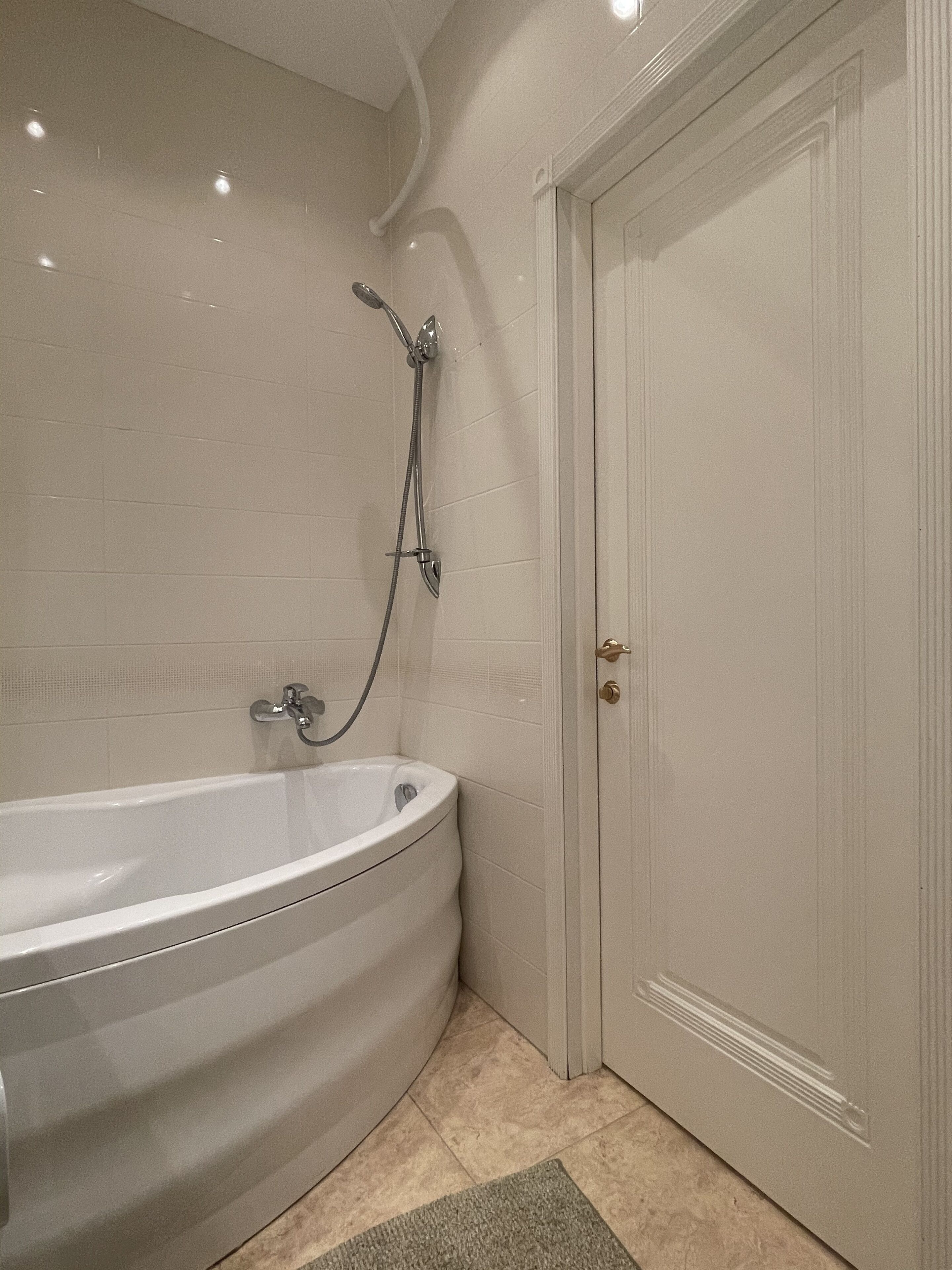 Ein Badezimmer mit einer freistehenden Badewanne, einer Duschbrause und einer Tür.