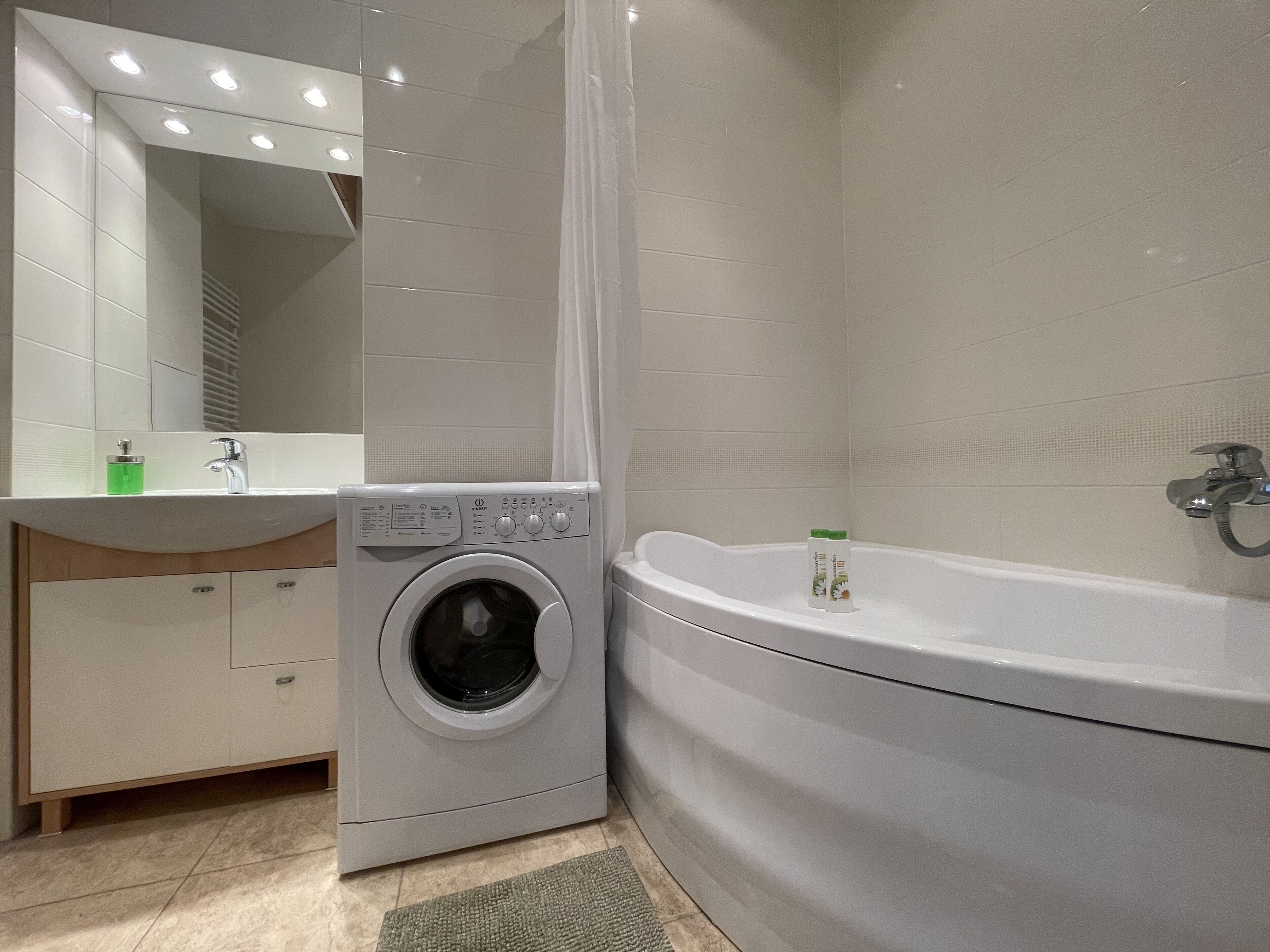 Uma casa de banho moderna com máquina de lavar integrada, toucador com espelho e banheira.