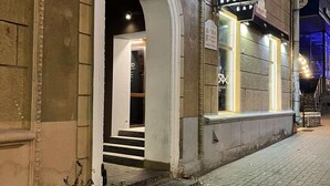 Un edificio con una entrada arqueada, un letrero con escritura cirílica y plantas en macetas en la acera.
