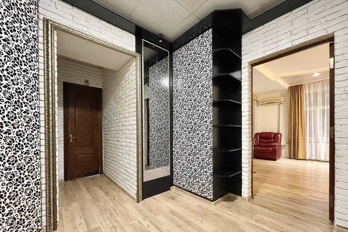 A hallway with white brick walls, black and white patterned panels, and a wooden floor.
