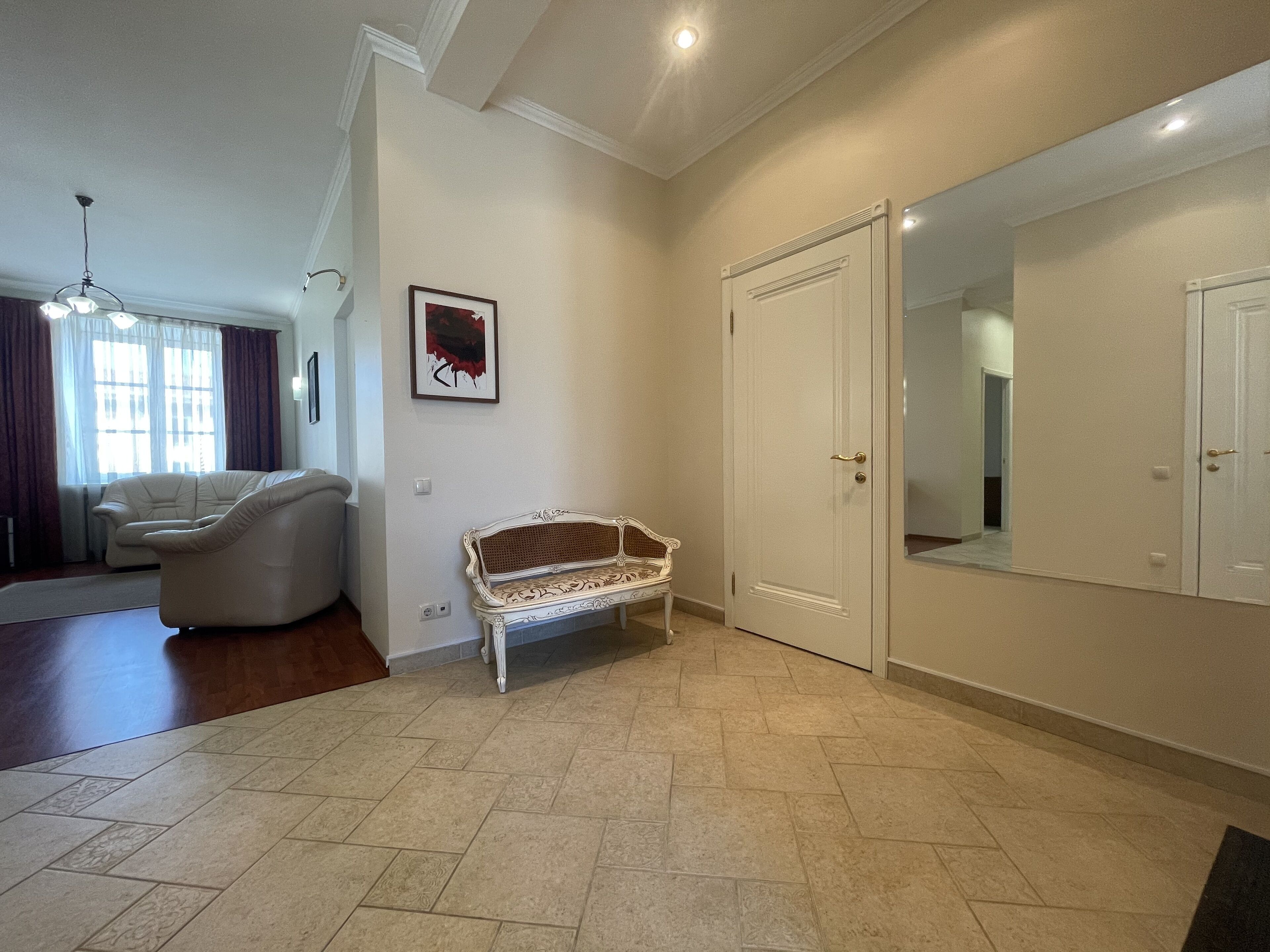 A spacious living room with a sofa, a bench, and a large mirror.
