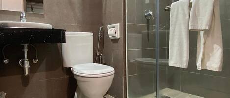A modern bathroom with a toilet, sink, and glass shower enclosure.