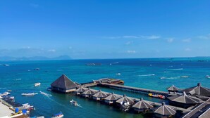 An overwater bungalows with a thatched roof, connected by a pier to the mainland. - Grace Hotel Semporna (Semporna)