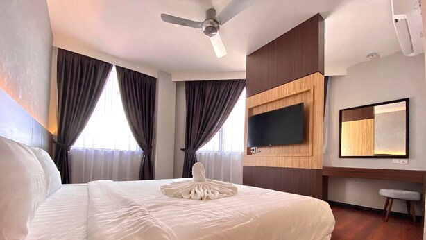 A hotel room with a large bed, a ceiling fan, a flat-screen TV, a mirror, and a small stool. - Grace Hotel Semporna (Semporna)