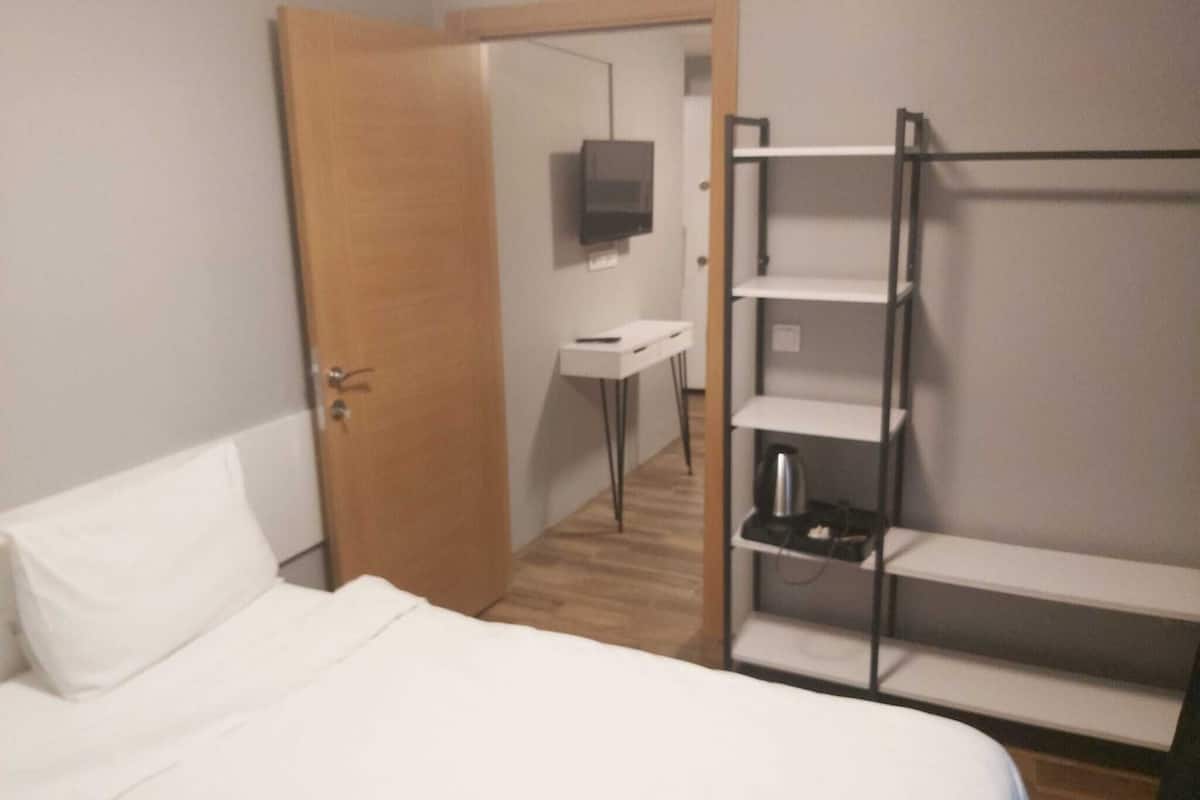 A hotel room with a bed, a desk, a TV, and a wardrobe.