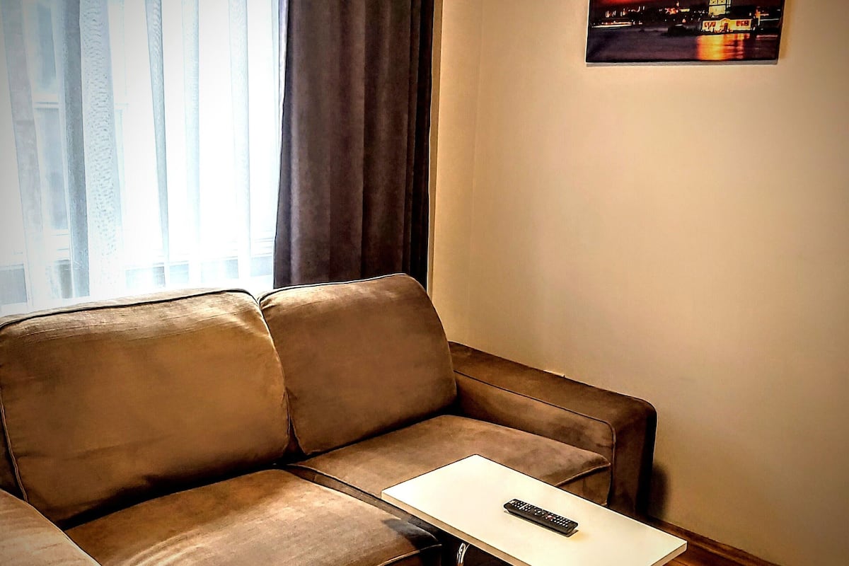 A brown leather sofa with a white coffee table and a remote control on it.