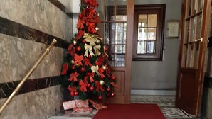Una escalera con alfombra roja que conduce a una puerta, un árbol de Navidad con adornos rojos y dorados, y una pared de mármol.