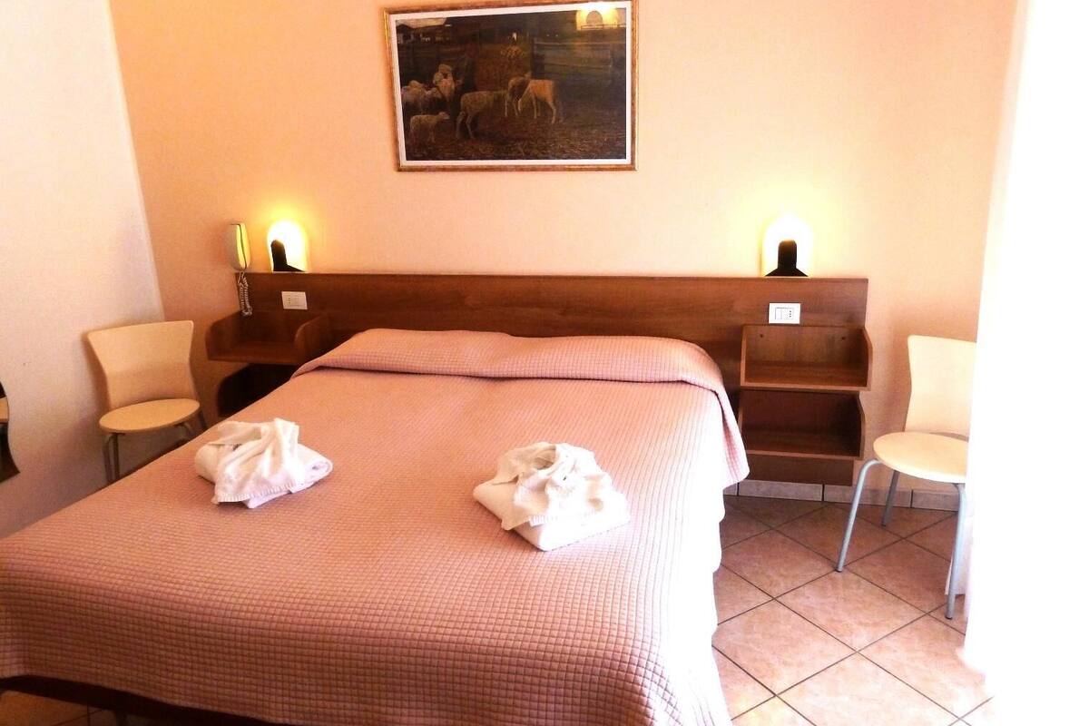 Une chambre d’hôtel avec un grand lit, deux tables de chevet avec des lampes, deux chaises et un tableau au mur.