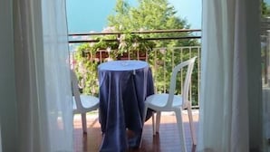 A balcony with a table and chairs, offering a view of a lake and mountains. - Hotel Baitone (Malcesine)