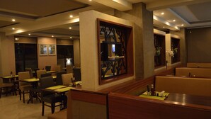 Un restaurante con mesasychairas, decoración de madera y una pantalla de televisión.