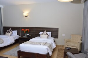 Una habitación de hotel con dos camas, una mesita de noche, una silla y una lámpara.