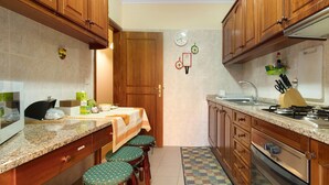 Cocina compacta con armarios de madera, encimera de granito y zona de comedor con taburetes.