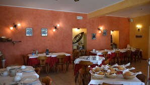 A dining area with tables set for meals, chairs, and baskets of bread. - Camping Alpino (Malcesine)