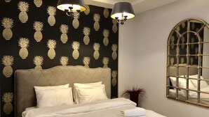 A neatly made bed with white linens and a folded towel, a headboard with a pineapple pattern, and two wall-mounted lamps. - HOME APART Storozhovskaya str. 6 (Minsk)