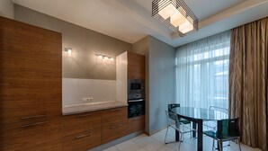 A modern kitchen with wooden cabinets, a built-in microwave, and a glass dining table with chairs. - HOME APART Storozhovskaya str. 6 (Minsk)