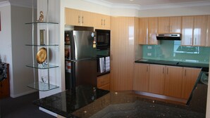 Eine moderne Küche mit Holzausstattung, einem Edelstahlkühlschrank, einer Mikrowelle und einem Glastageslichtschrank.