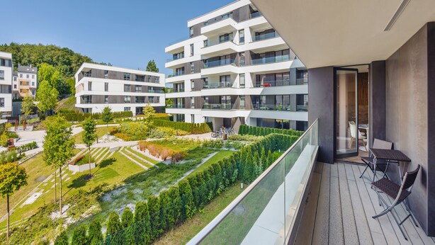 Un immeuble d’appartements moderne doté d’un balcon, d’un jardin et offrant une vue sur les environs.