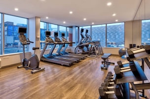A modern gym with treadmills, elliptical machines, and free weights.