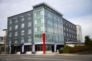 Un bâtiment Holiday Inn Express & Suites au design moderne, doté de grandes fenêtres et d’une entrée rouge et blanche bien visible.
