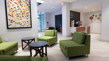 Decoração moderna com assentos estofados em verde, um espaço para café e uma obra de arte geométrica colorida na parede.