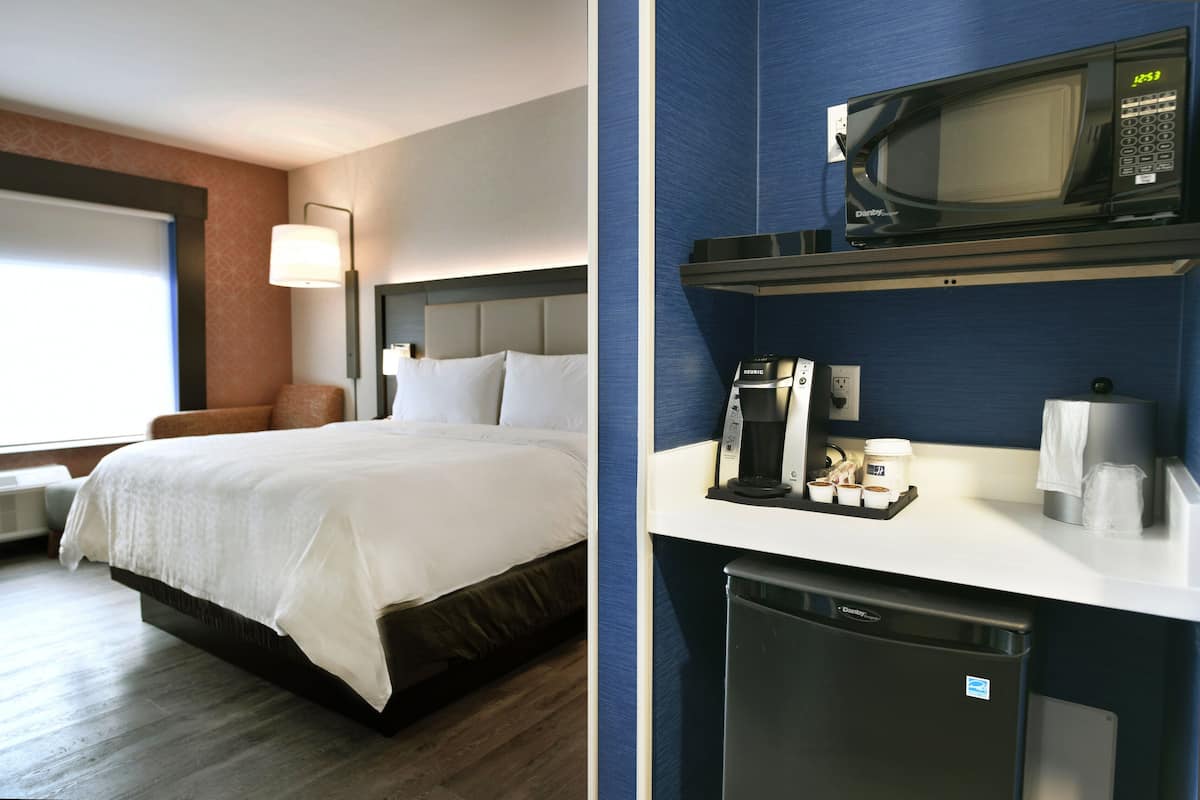 Ein Hotelzimmer mit einem Bett, einem Schreibtisch mit Mikrowelle, einer Kaffeemaschine und einem Mülleimer.