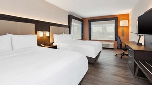A hotel room with two beds, a desk, a chair, a TV, and a large window with a city view.