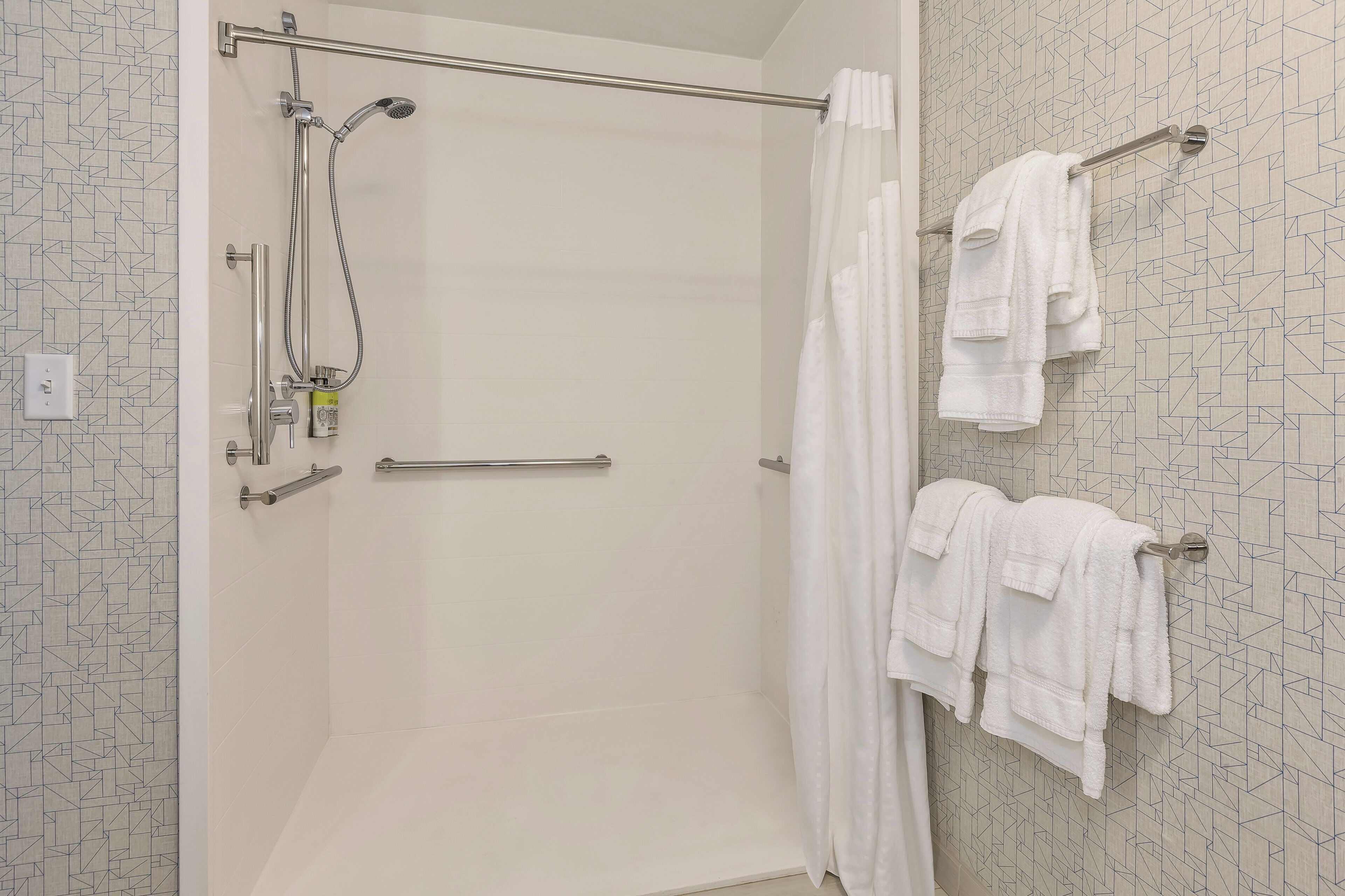 Une douche avec une porte en verre, un porte-serviettes avec des serviettes et un panneau de commande de la douche.