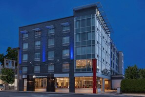 A modern hotel with a glass facade, multiple floors, and a visible entrance with a sign. - Holiday Inn Express & Suites Jersey City - Holland Tunnel by IHG (Jersey City)