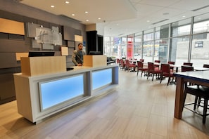 A hotel reception area with a modern design, featuring a reception desk, seating area, and large windows providing views of the street. - Holiday Inn Express & Suites Jersey City - Holland Tunnel by IHG (Jersey City)