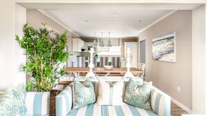 A modern living room with a sofa set, a dining table, and a kitchen in the background. - Villa Nikos J-Bay (Jeffreys Bay)