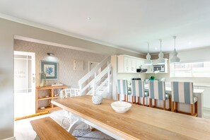 A modern kitchen with white cabinets, a wooden dining table, and striped chairs.
