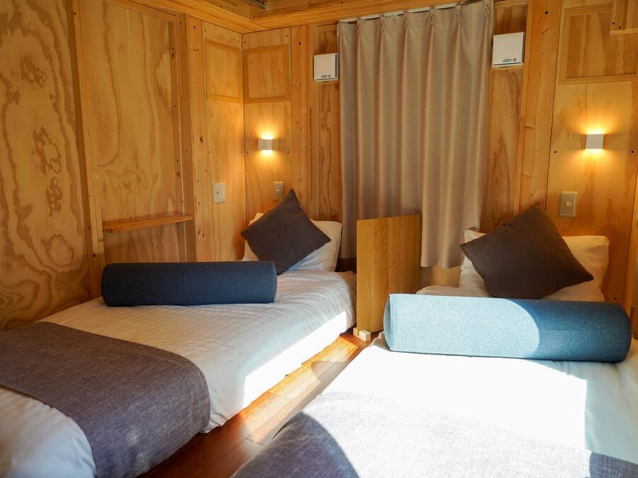 Une chambre dans un chalet en bois, avec deux lits, chacun étant équipé d’oreillers et d’une couverture.