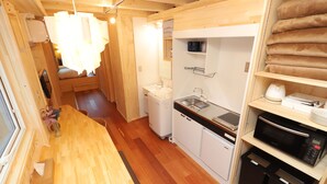 A compact kitchen with wooden cabinets, a sink, a microwave, and a refrigerator. - JR Mobile Inn Sapporo Kotoni (Sapporo)