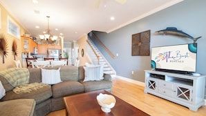 A modern living room with a sectional sofa, a wooden coffee table, and a television on a white entertainment unit. - 3BR/3BA Oceanview just steps from the sand~ 107 Ocean Pointe (Folly Beach)