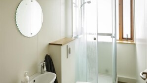 Een badkamer met een douchecabine van glas, een wit wastafel en een toilet.