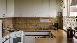 Een keuken met witte kasten, een fornuis, een spoelbak en een koffiezetapparaat.
