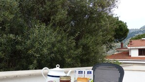 A table with a tray set for tea, including cups, a teapot, a jar of honey, and biscuits, set against a backdrop of trees and a building. - Le Stanze dellArte (Palermo)