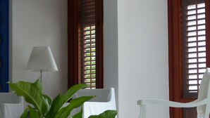 A room with a bed, a white chair, a lamp, and a window with wooden shutters. - Le Stanze dellArte (Palermo)