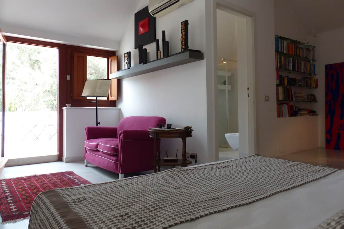 A bedroom with a bed, a desk, a chair, a bookshelf, and a window.