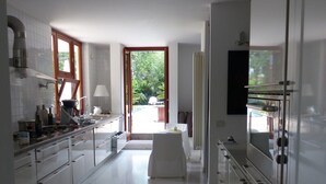 A modern kitchen with white cabinets, a central island, and a view of the outdoors through a glass door. - Le Stanze dellArte (Palermo)