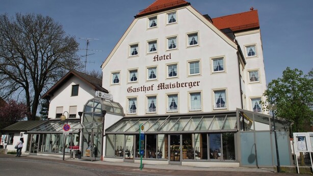 Un hotel con un gran letrero que dice 'Hotel Gasthof Maisberger' en un edificio blanco con varias ventanas.