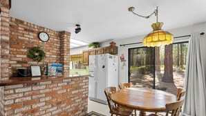 Eine Küche mit Backsteinwand, einem Holztisch und einem Kühlschrank.